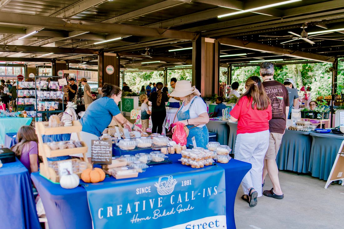 Vendors and shoppers inside the covered pavilion at Market at the Rail District, with home-baked goods for sale.