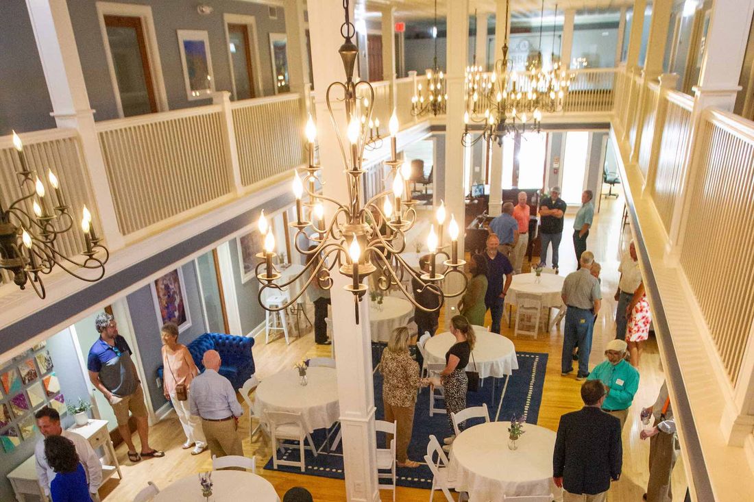 Guests at an event in Abbott Atrium, seen from the balcony above, with chandeliers hanging over round and high-top tables.