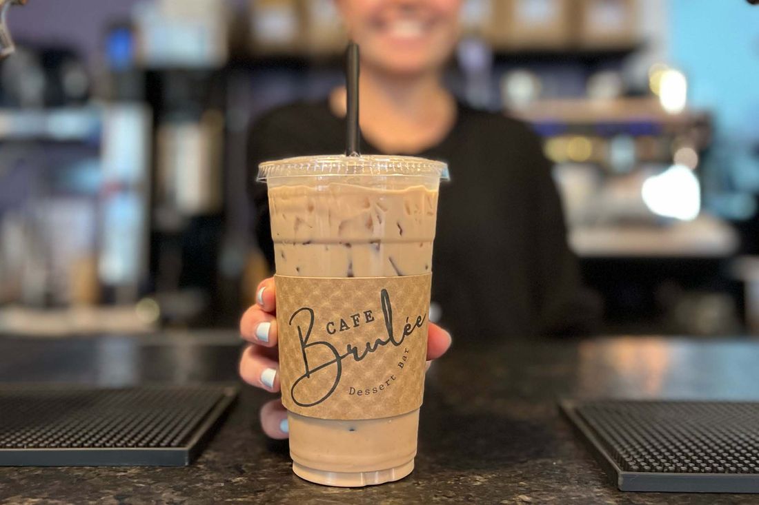An iced coffee in a Café Brûlée branded cup.